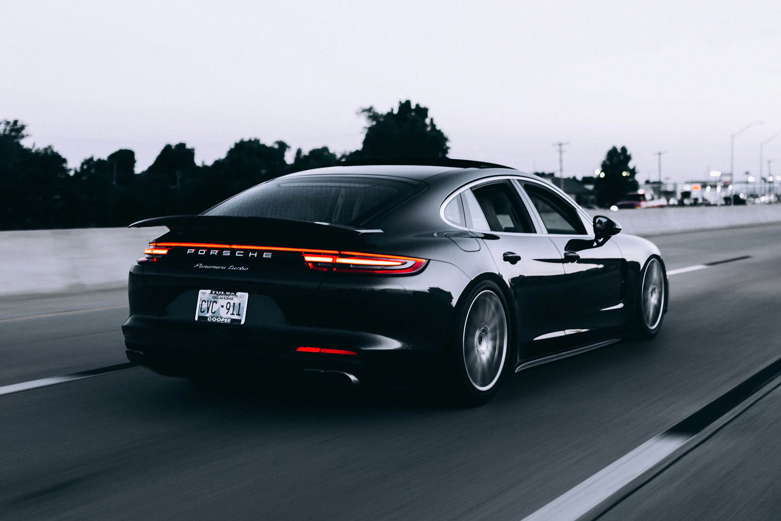 A black sports car speeding along a motorway at dusk