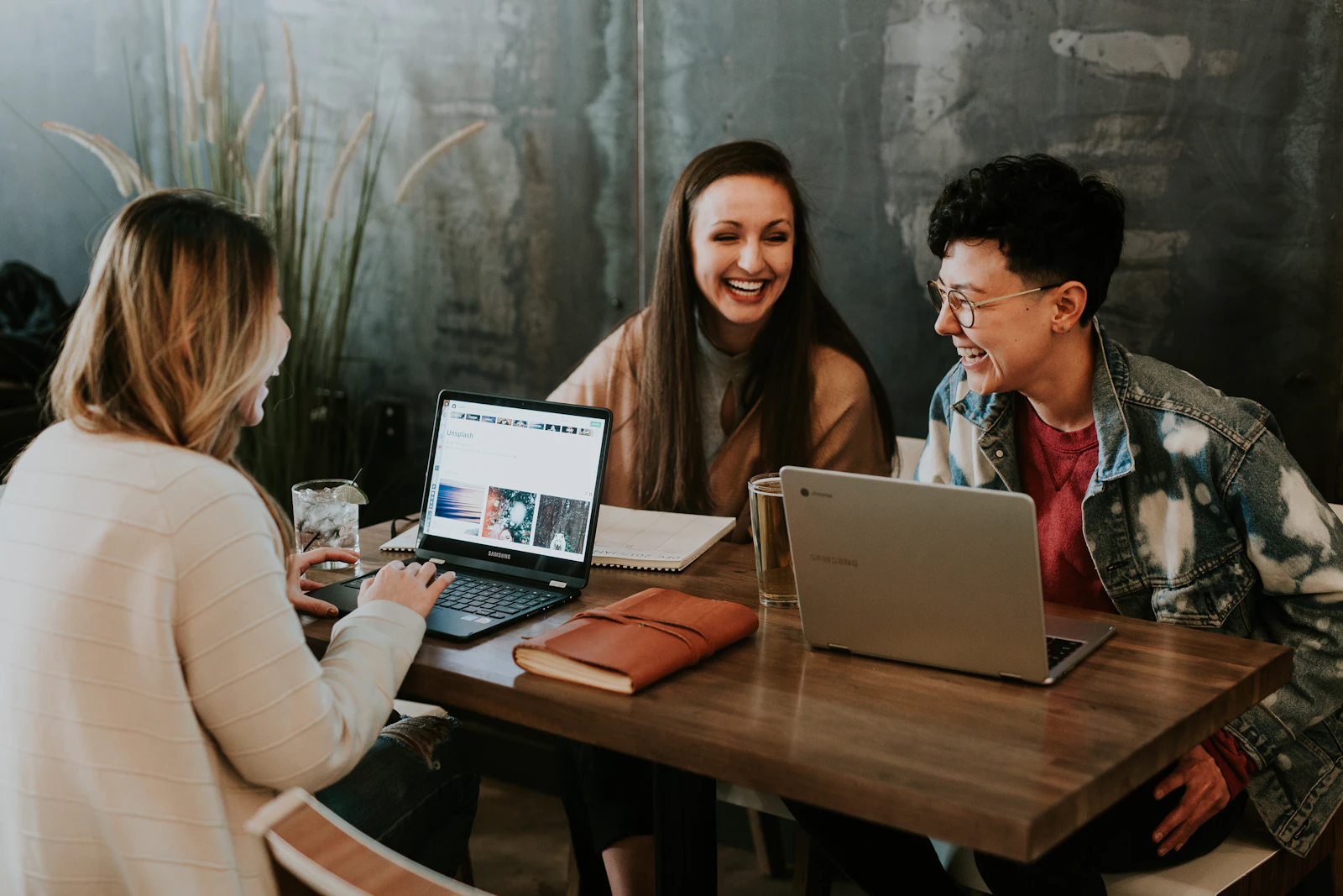 Three colleagues working together at laptops around a wooden table